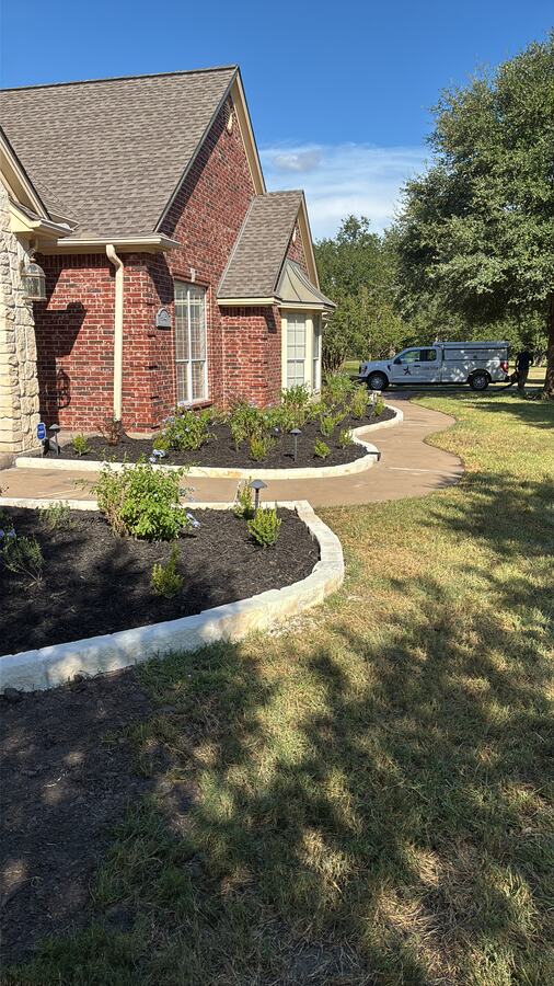 Brick home frontage with a curved bed, retaining wall and mown lawn