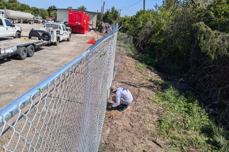 Installer setting chain link fabric on a commercial site