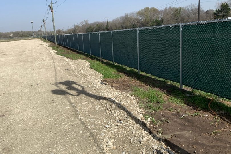 Chain link fence with green privacy screening along a property line