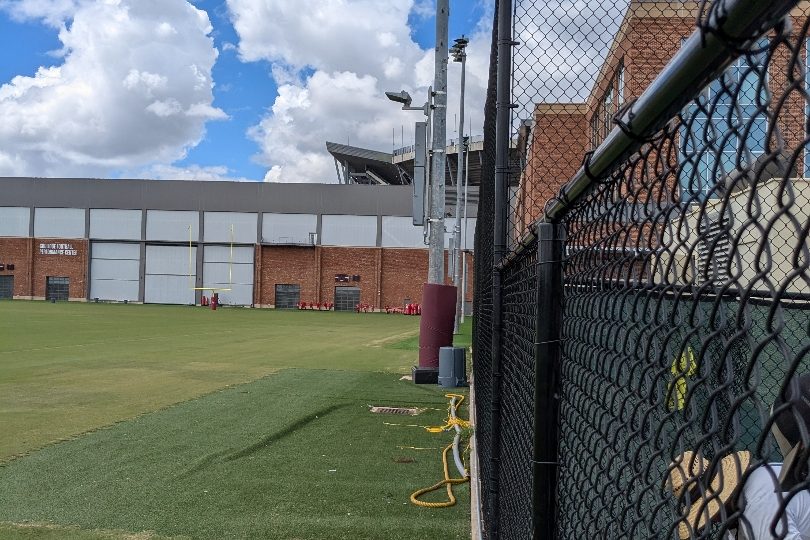 Black chain link fencing alongside an athletic field at a Texas A&M facility