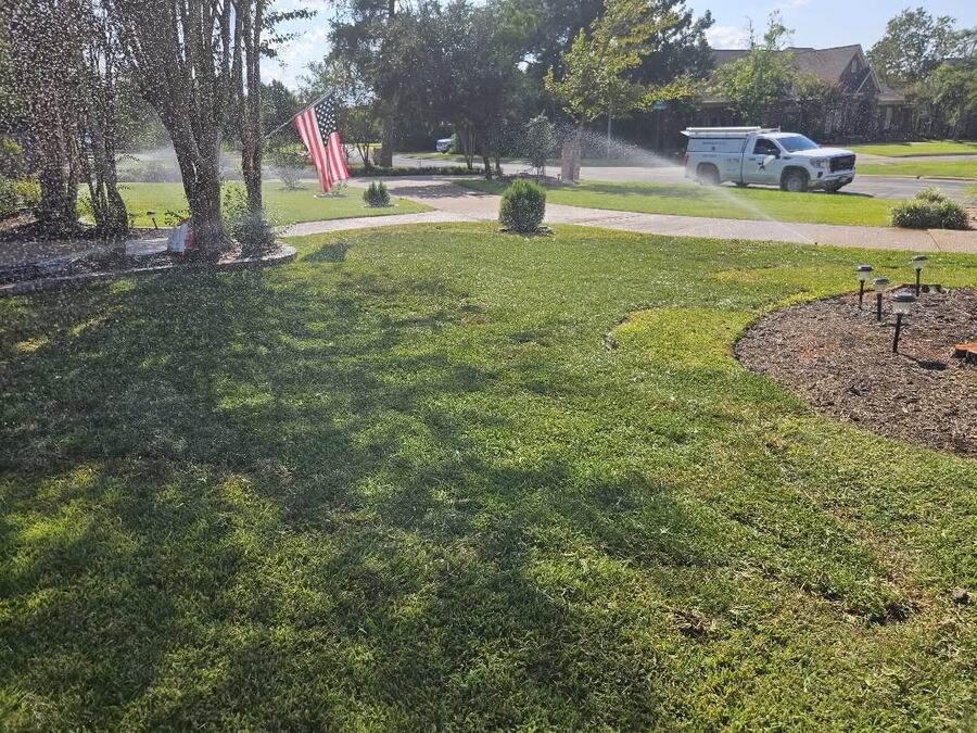 Irrigation running across a large front lawn on a Brazos Valley property