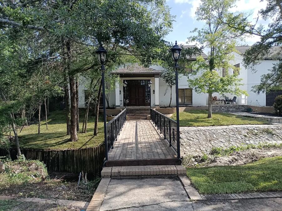 Wooded front entry with a footbridge, flagstone walk and path lighting