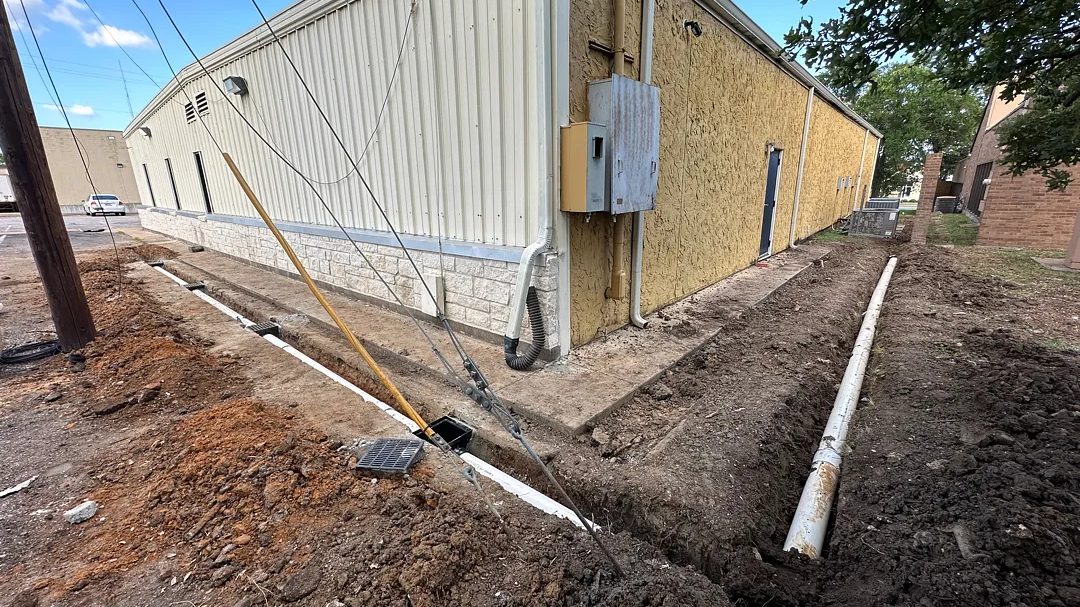 Drainage trench with new pipe running alongside a commercial building