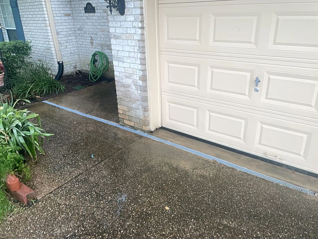 Channel drain set along a driveway beside a garage door