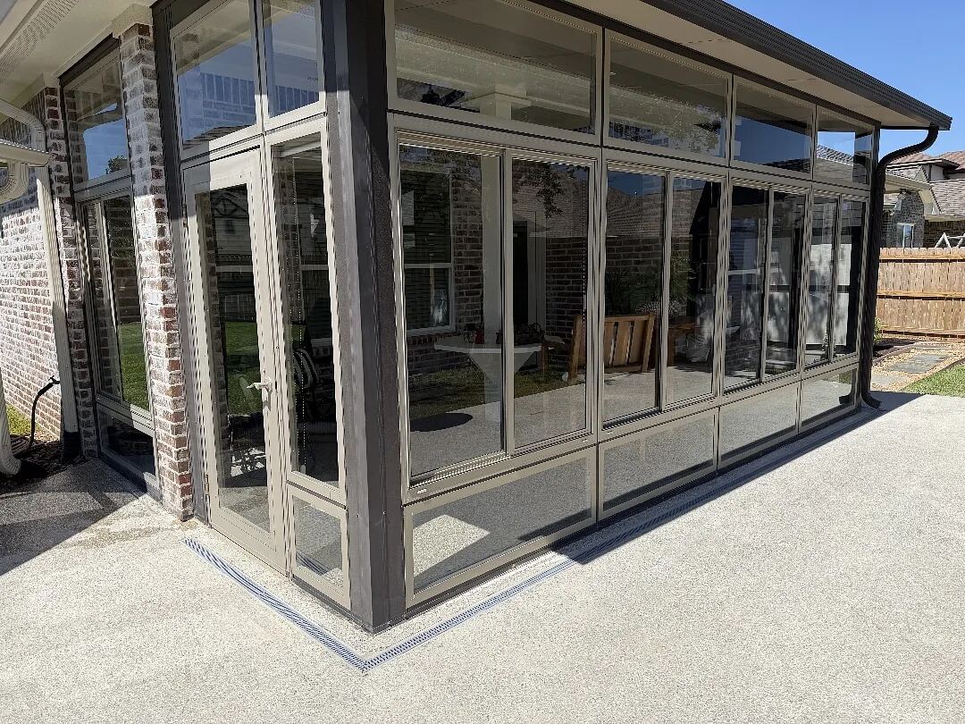 Channel drain run along the base of a glassed patio enclosure