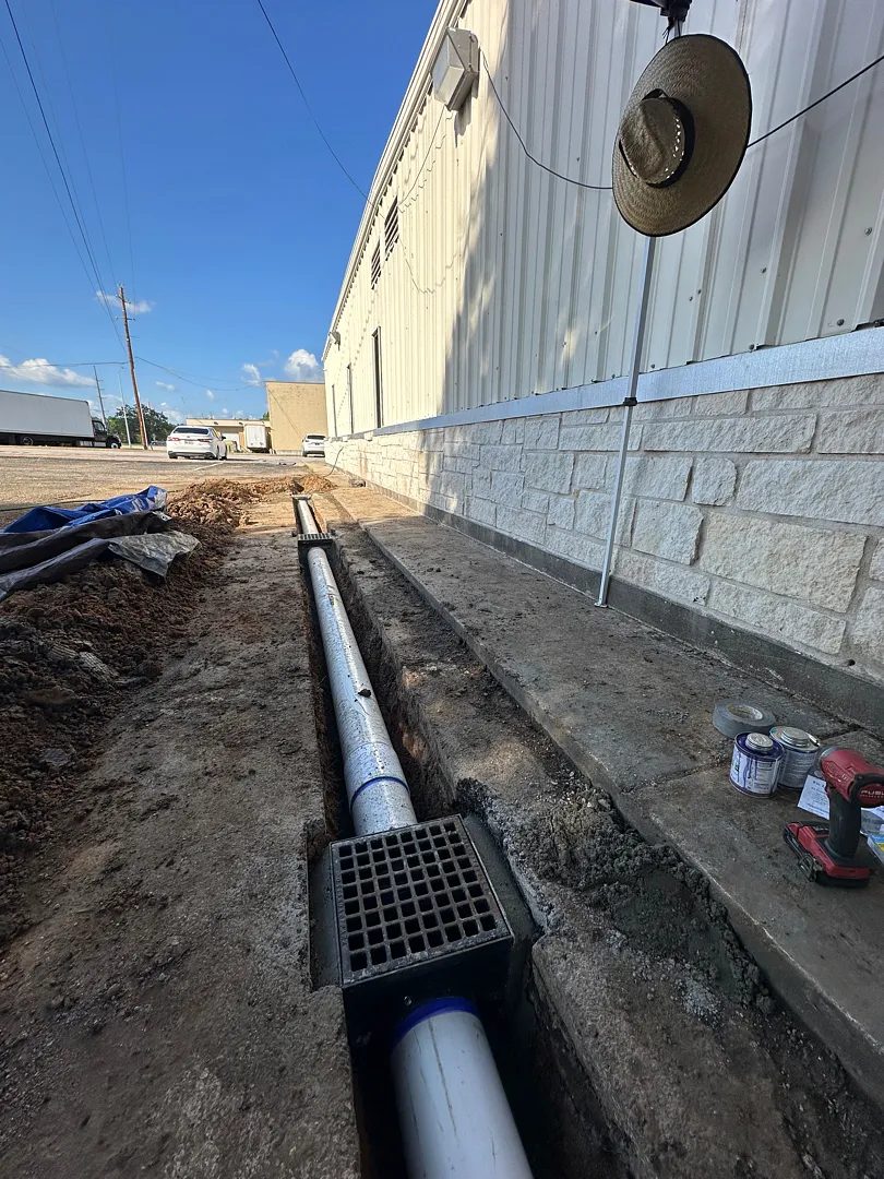 Finished channel drain grate set against a commercial building wall