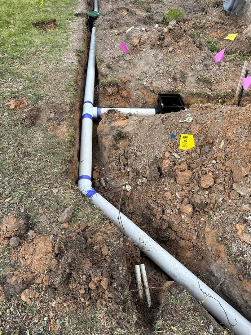 Irrigation mainline trenched in with marking flags on a Brazos Valley property