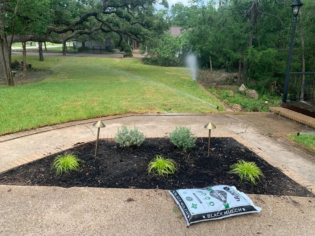 Irrigation running over newly laid sod and a fresh planting bed