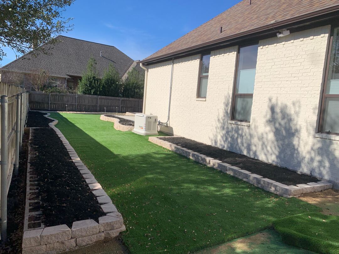 Artificial turf side yard with brick edging alongside the house