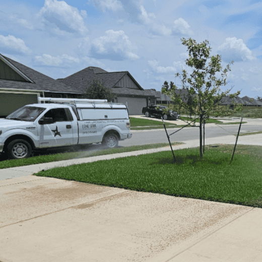 Lone Star Property Services truck parked at a residential job site beside a newly planted tree and established turf